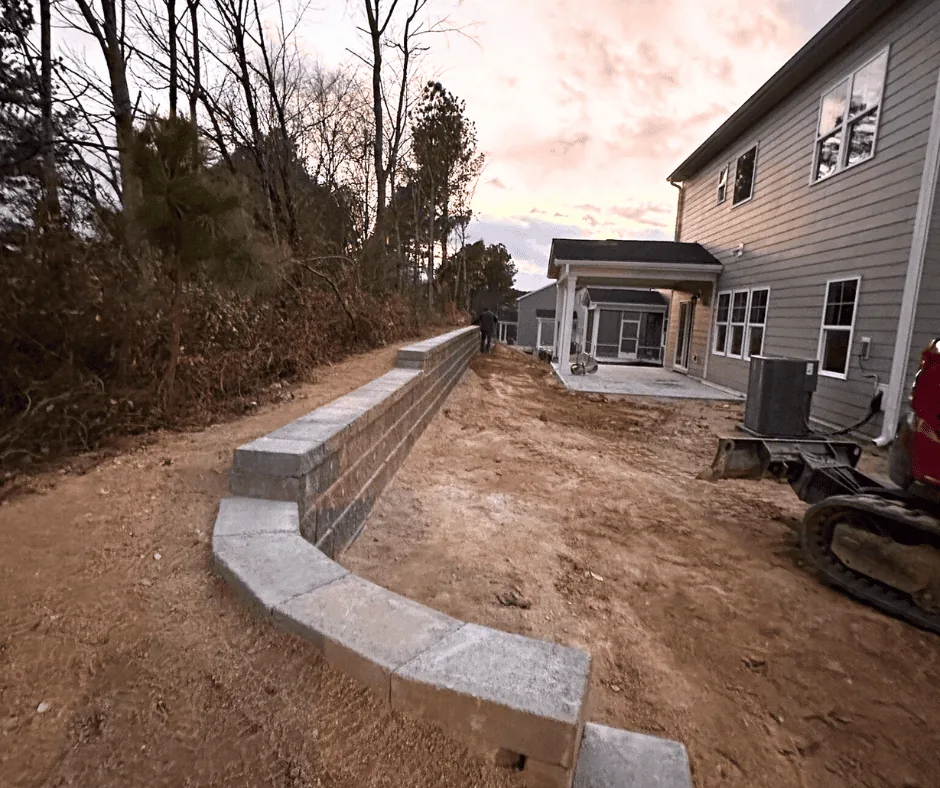 Curved retaining wall stabilizing a graded slope at dusk