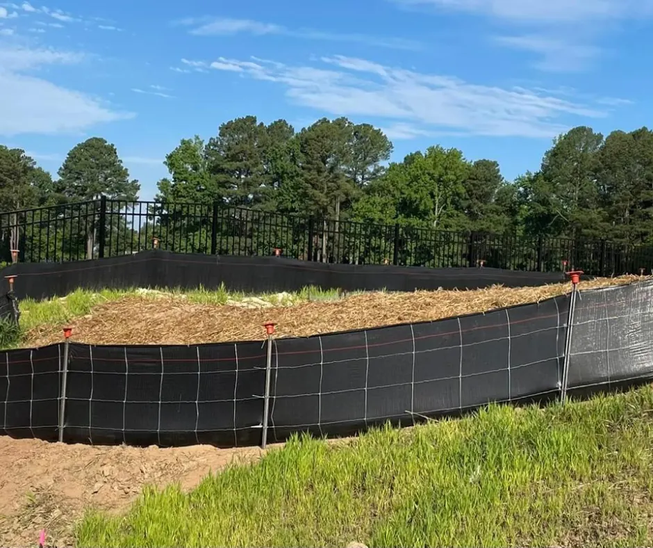 Silt fence installation along a tree line on a construction site